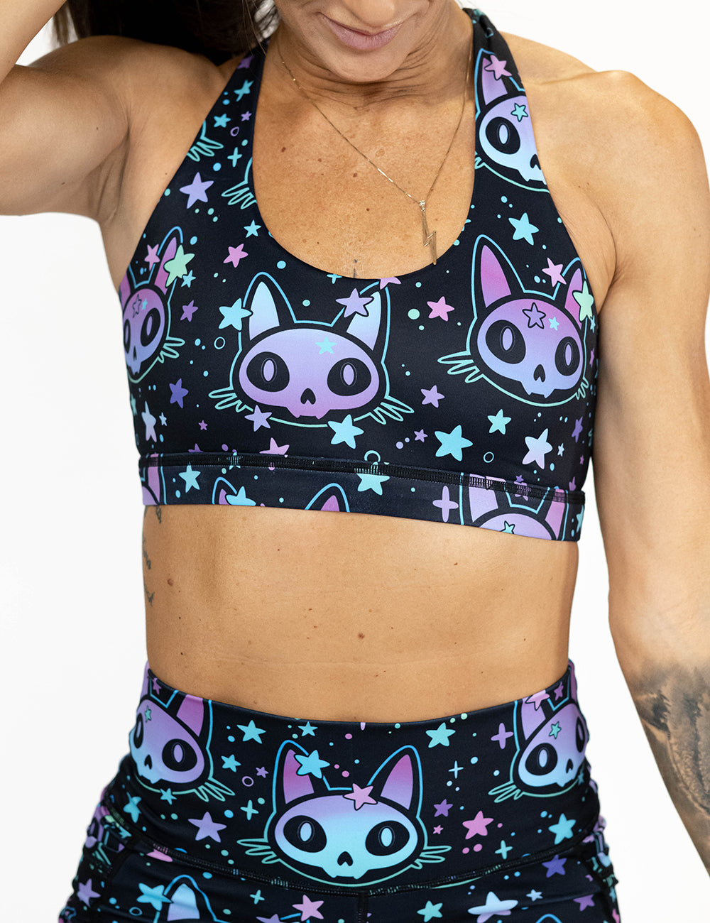 front of alien cat with stars print butterfly back bra against a white background
