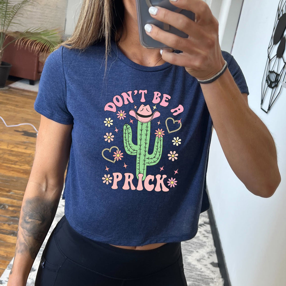 heather navy cropped tee with a cactus wearing a cowboy hat graphic on it that says "Don't Be A Prick"