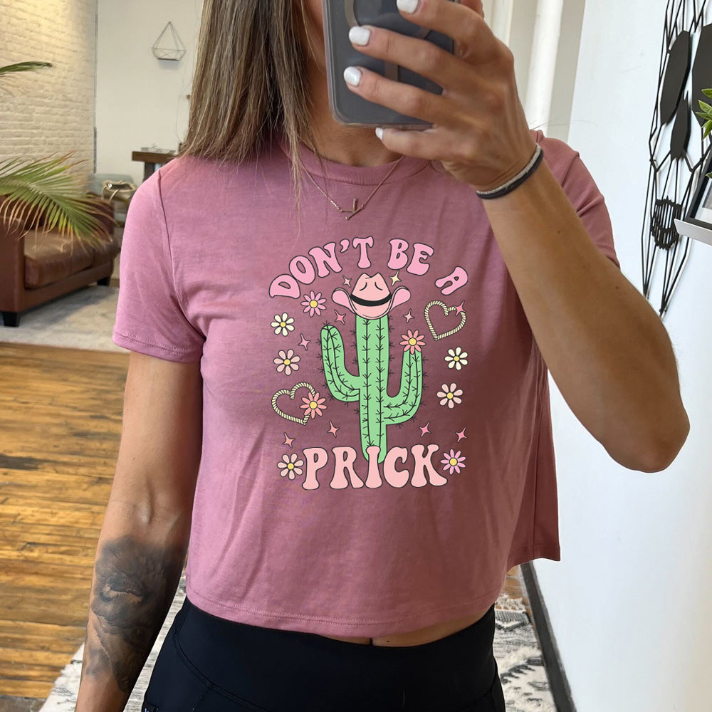 mauve cropped tee with a cactus wearing a cowboy hat graphic on it that says "Don't Be A Prick"