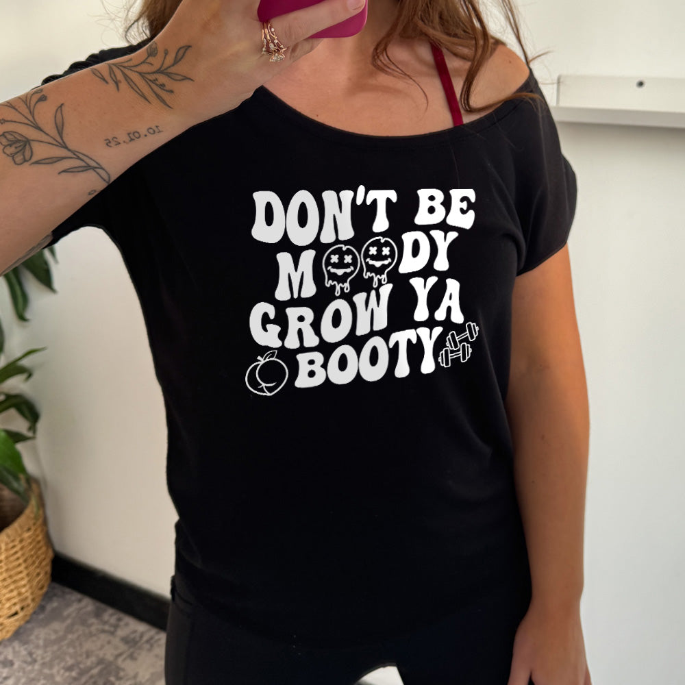 slouchy tee with the words "Don't Be Moody Grow Ya Booty" in white lettering, the o's are emojis, and there's a peach and two barbells