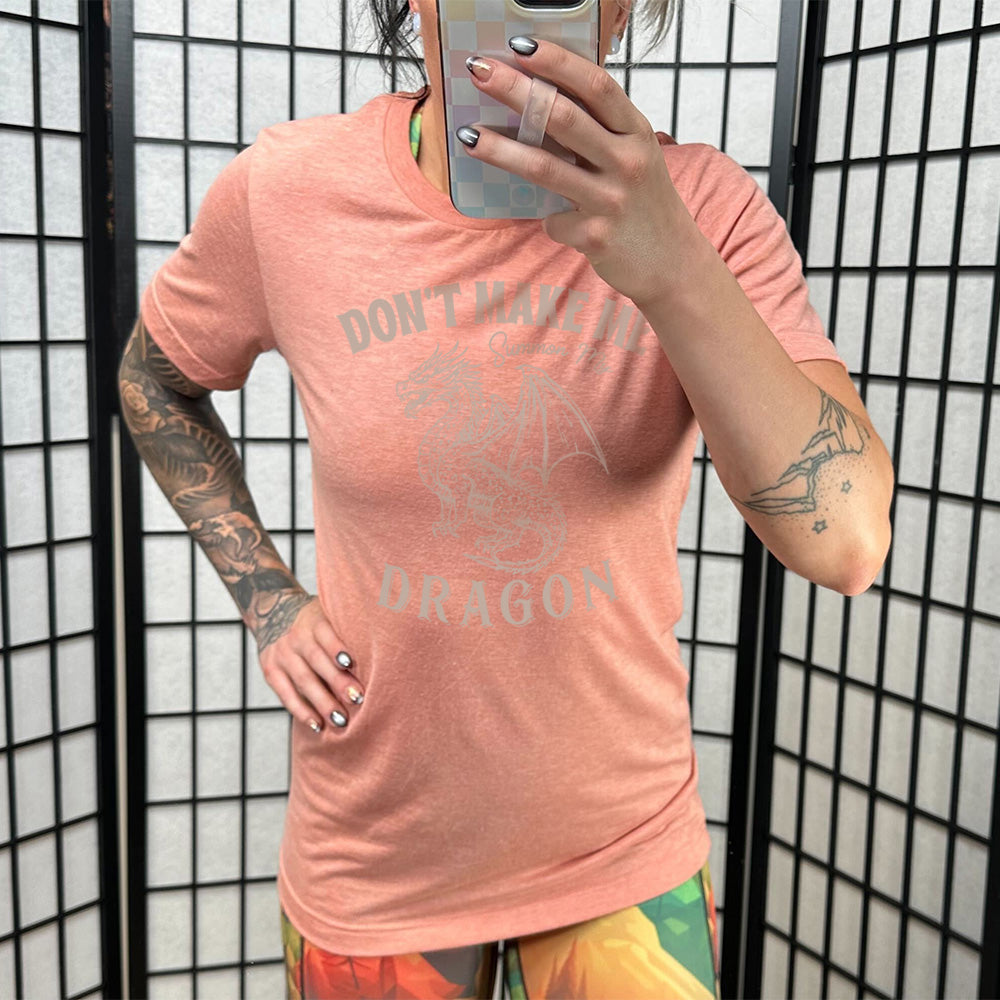 sunset unisex tee with the words "don't make me summon my dragon" on it, surrounding the graphic of a fierce-looking dragon