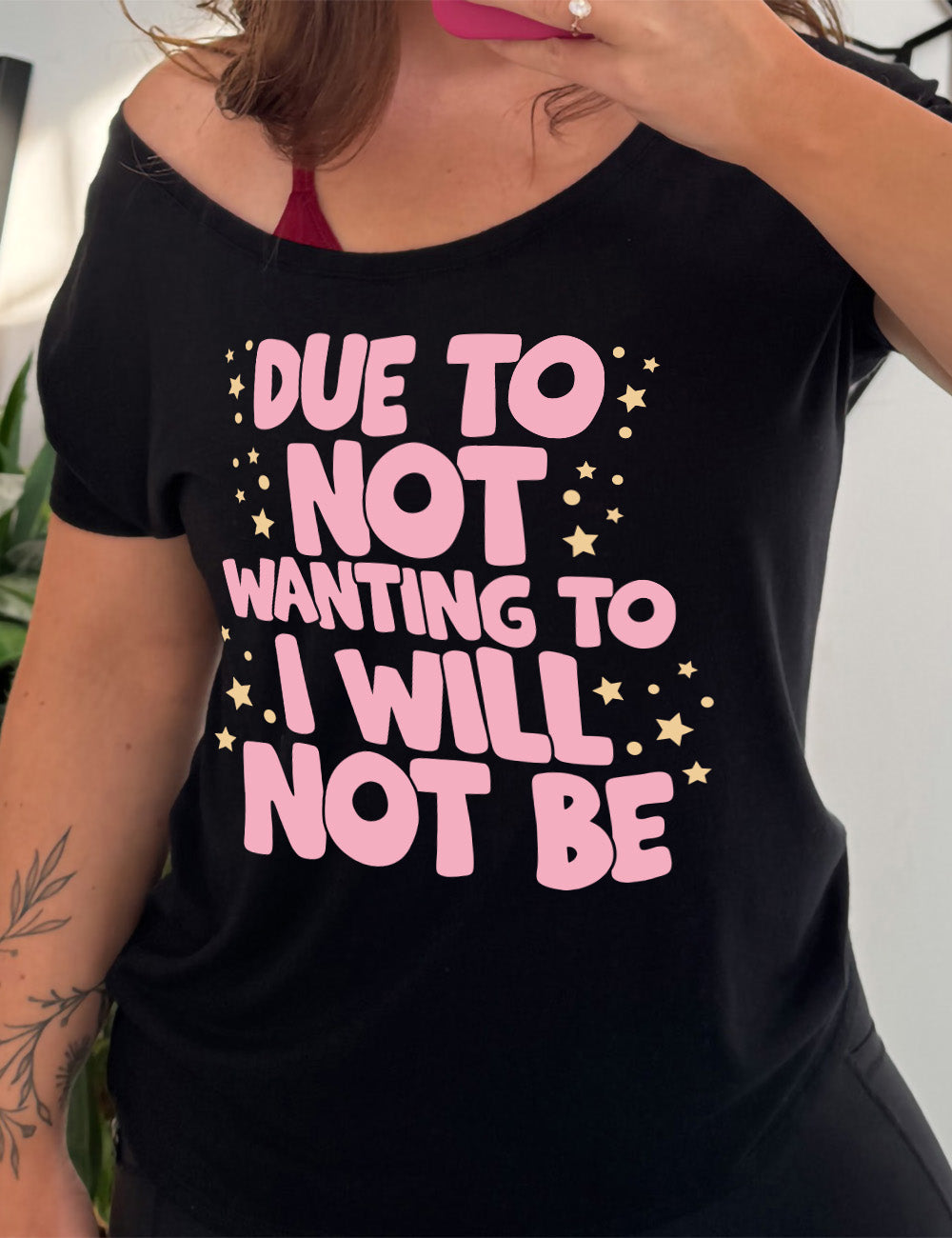 black slouchy tee with the wording saying "due to not wanting to I will not be" in thick font, with many star and dot graphics around it