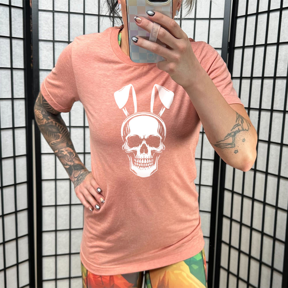 Sunset colored shirt with a skull wearing bunny ears graphic on it