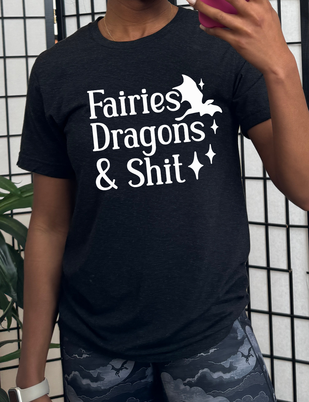 black unisex tee with the words "fairies dragons & shit" on it, with the small graphic of a dragon and a few stars