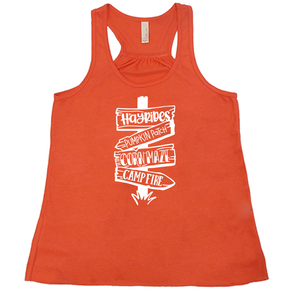 Coral colored flowy tank with fall activities signpost graphic on it that says "Hayrides, Pumpkin Patch, Corn Maze, Campfire"