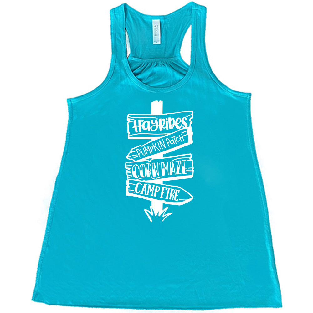 Teal colored flowy tank with fall activities signpost graphic on it that says "Hayrides, Pumpkin Patch, Corn Maze, Campfire"