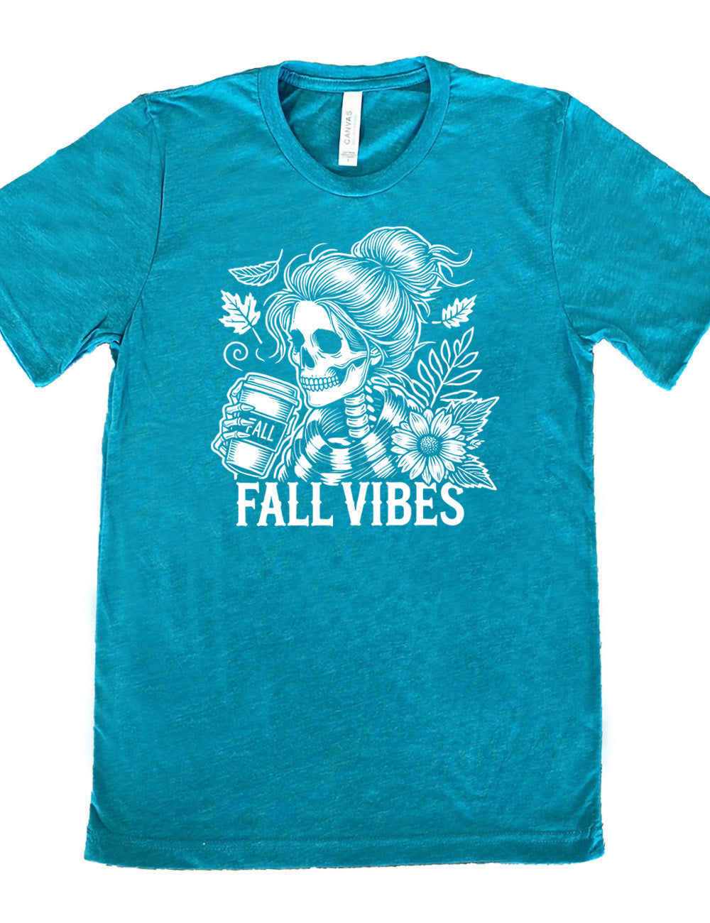 teal unisex tee with the graphic of a skeletal woman, with her hair in a bun, holding a takeaway coffee cup labeled "fall", with a flower and leaves next to her, and the words underneath saying "fall vibes"