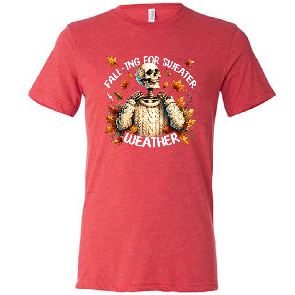 Red colored shirt with fall leaves and skeleton wearing a sweater graphic on it that says "Fall-ing For Sweater Weather"