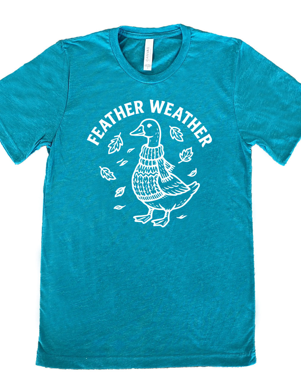 teal unisex tee with the graphic of a goose, wearing a scarf and sweater, surrounded by falling leaves, and the words arched over it saying "feather weather"