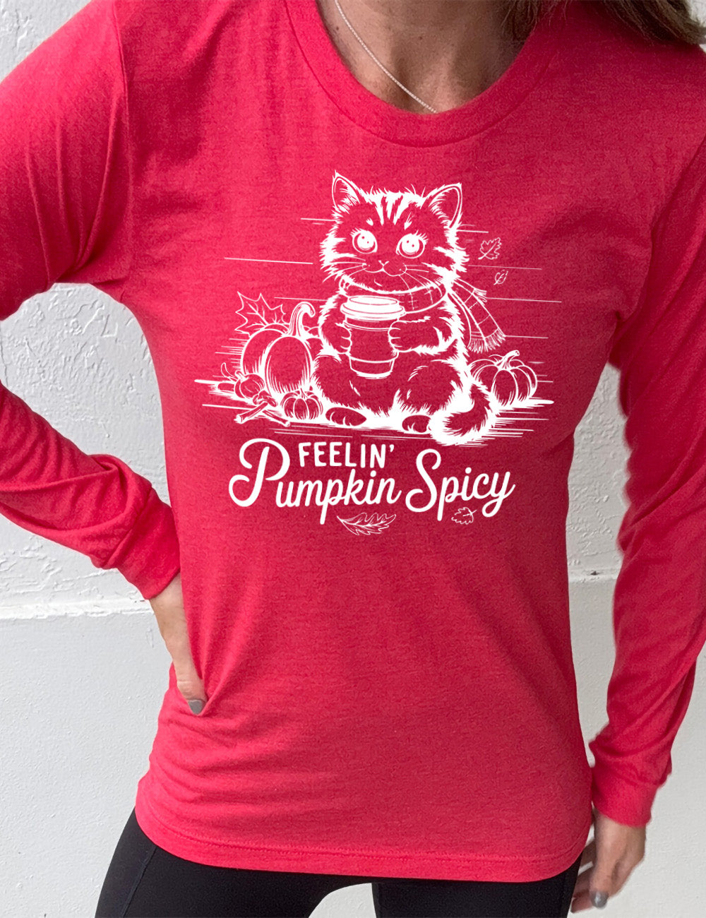 heather red long sleeve with the graphic of a cat, wearing a scarf, next to a few pumpkins of various sizes and a few falling leaves, holding a takeaway coffee, and the words underneath saying "feelin' pumpkin spicy"
