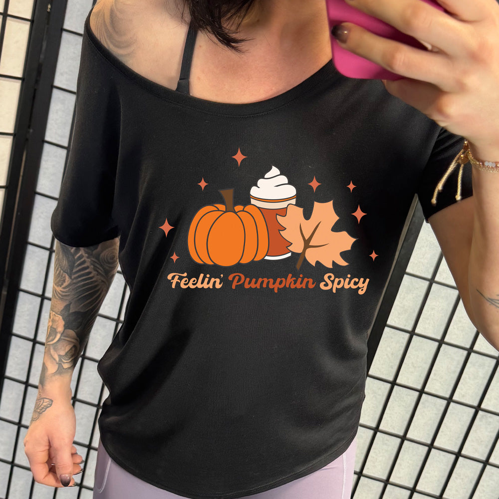 Person wearing a black t-shirt with a pumpkin and coffee design and 'Feelin' Pumpkin Spicy' text