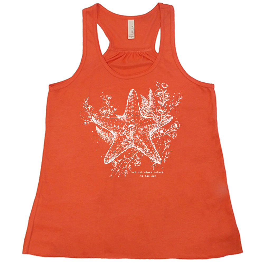 coral racerback flowy tank with the graphic of a very detailed starfish among sea plants and flowers, with little bubbles, and the small words underneath it all that say "not all stars belong to the sky"
