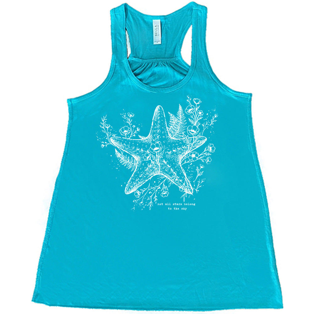 teal racerback flowy tank with the graphic of a very detailed starfish among sea plants and flowers, with little bubbles, and the small words underneath it all that say "not all stars belong to the sky"