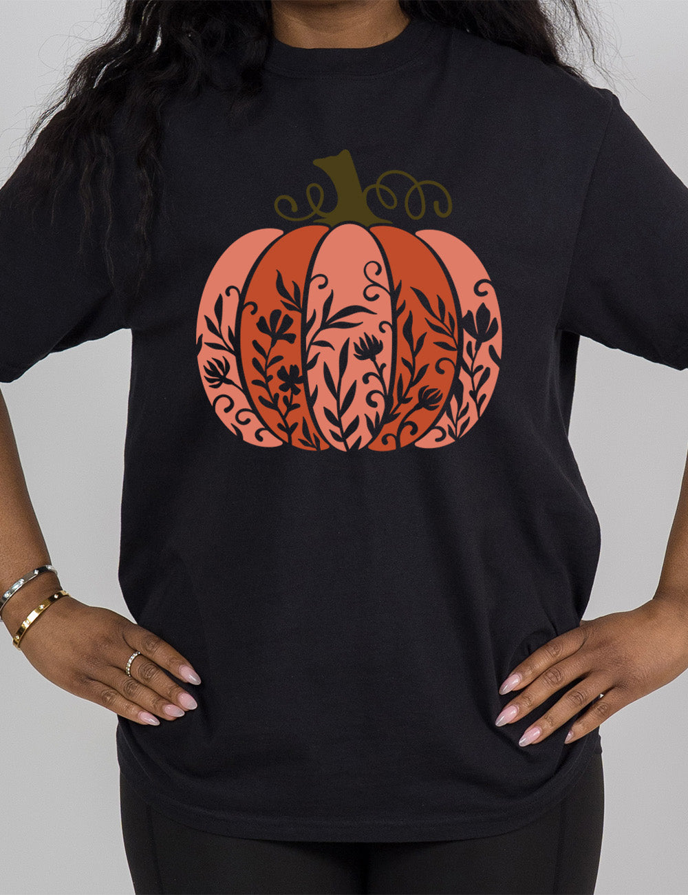 black modern tee with the colorful graphic of a pumpkin, with vines in silhouette on it