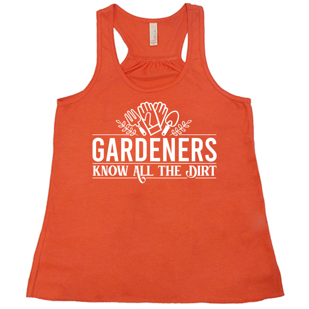 coral flowy racerback tank with the words "gardeners know all the dirt" on it, with the graphic of two gloves and two tools above the words