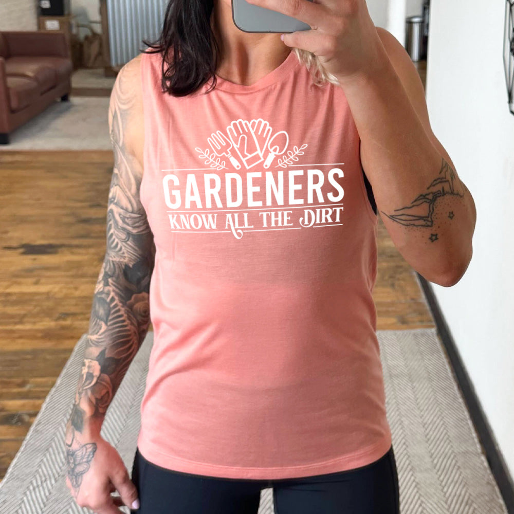 peach muscle tank with the words "gardeners know all the dirt" on it, with the graphic of two gloves and two tools above the words