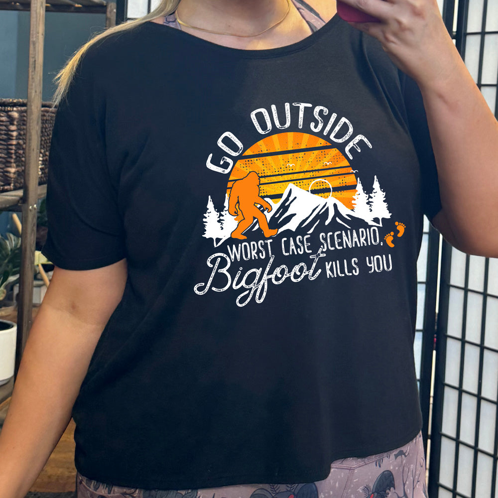 shirt with sun and bigfoot in mountains graphic on it that says "Go Outside, Worst Case Scenario Bigfoot Kills You"