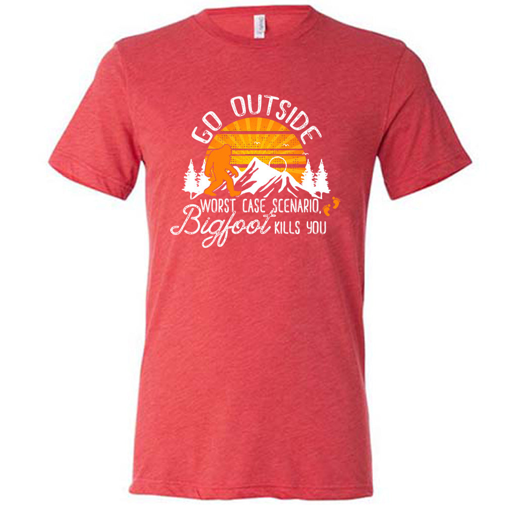 Red colored shirt with sun and bigfoot in mountains graphic on it that says "Go Outside, Worst Case Scenario Bigfoot Kills You"