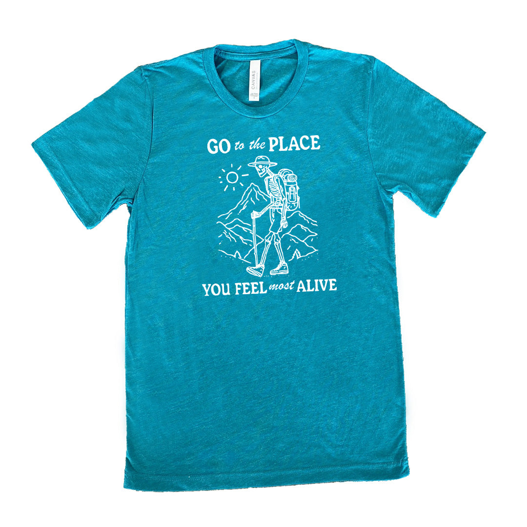 Teal colored shirt with a skeleton on a hike graphic on it that says "Go To The Place You Feel Most Alive"