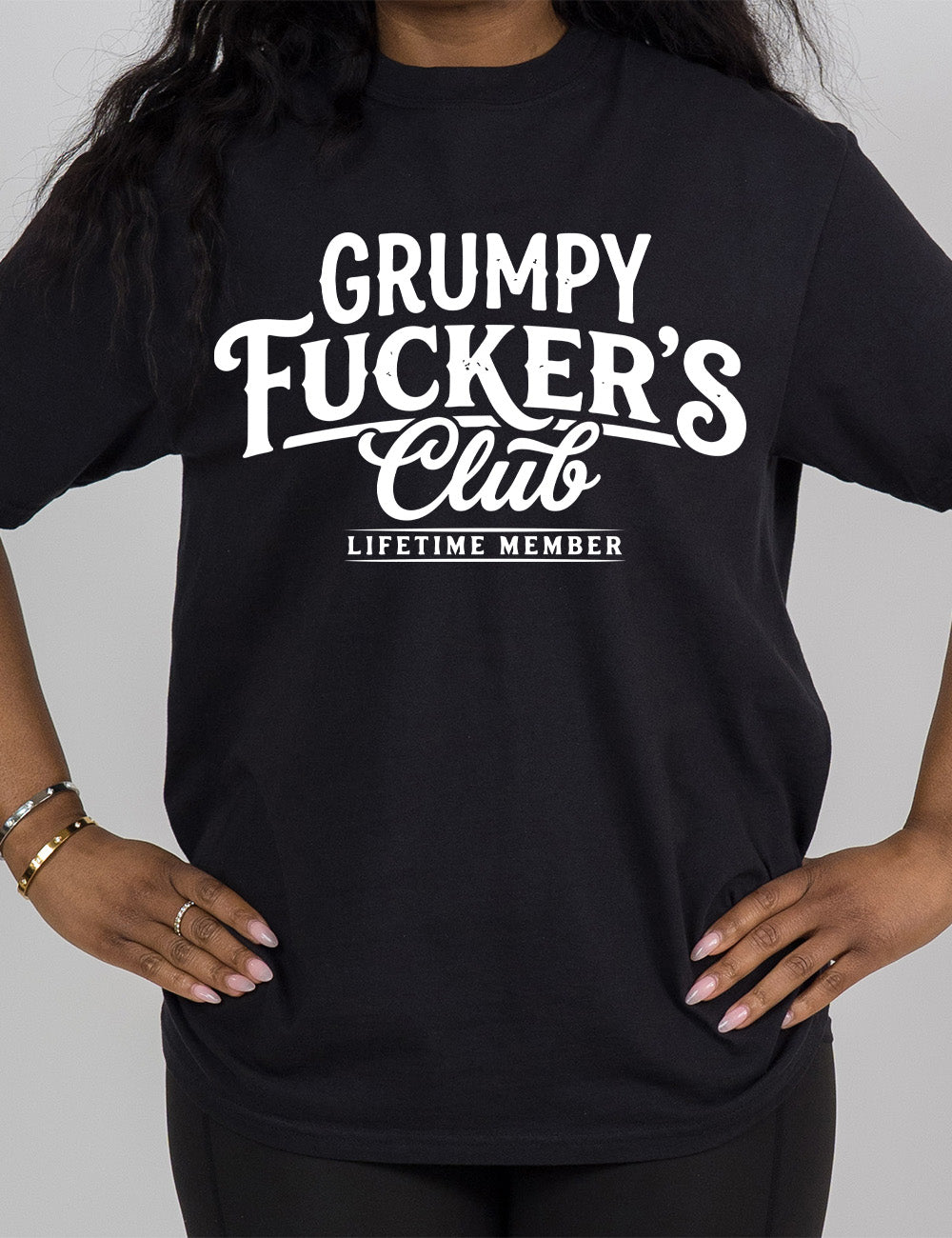 black modern tee with the words "grumpy fucker's club" on it, with smaller bannered words underneath saying "lifetime member"