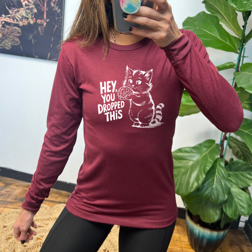 heather cardinal long sleeve with the words "Hey, you dropped this" and the graphic of a racoon holding a brain