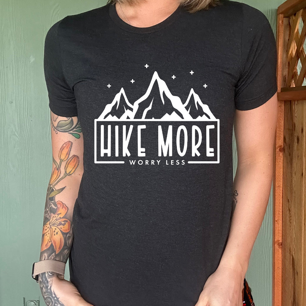 Black colored shirt with a mountains and stars graphic on it that says "Hike More Worry Less"