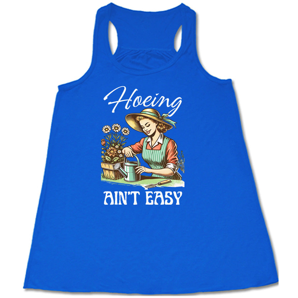 Blue colored flowy tank with a woman gardening graphic on it that says "Hoeing Ain't Easy"