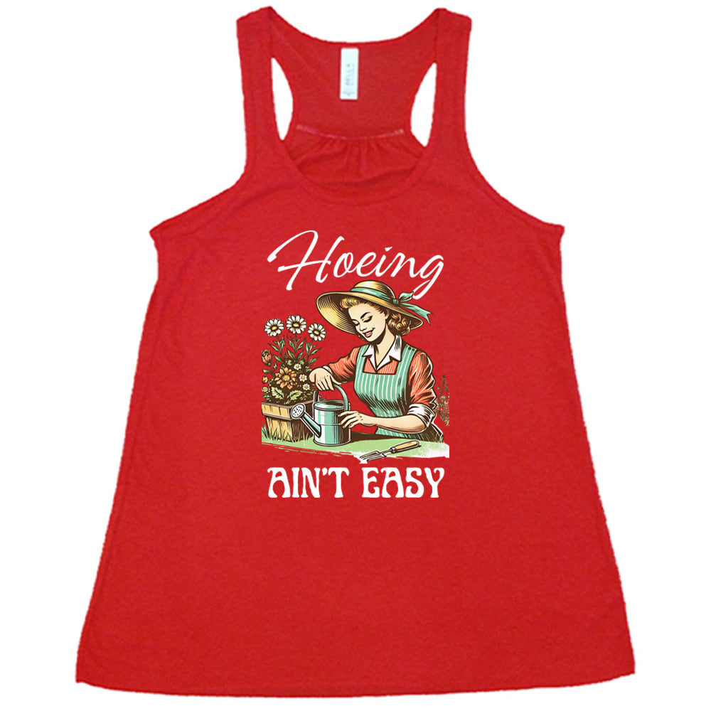 Red colored flowy tank with a woman gardening graphic on it that says "Hoeing Ain't Easy"