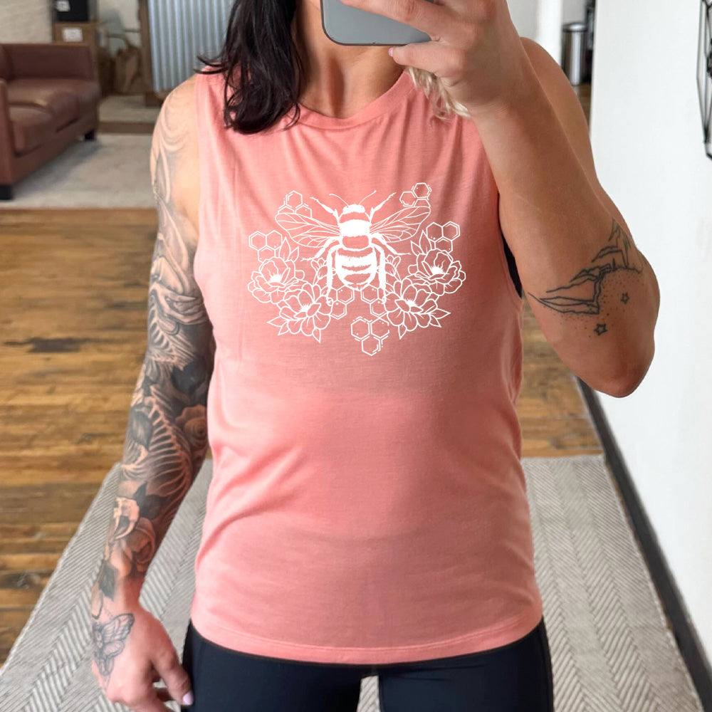 Peach colored muscle tank with a bee, honeycomb, and flower graphic on it