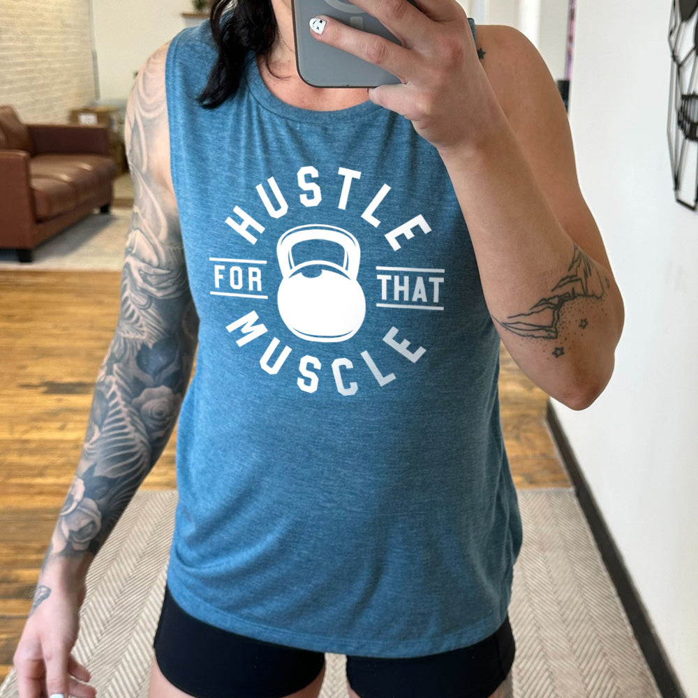 deep teal muscle tank with the words "hustle for that muscle" on it, with a kettlebell image