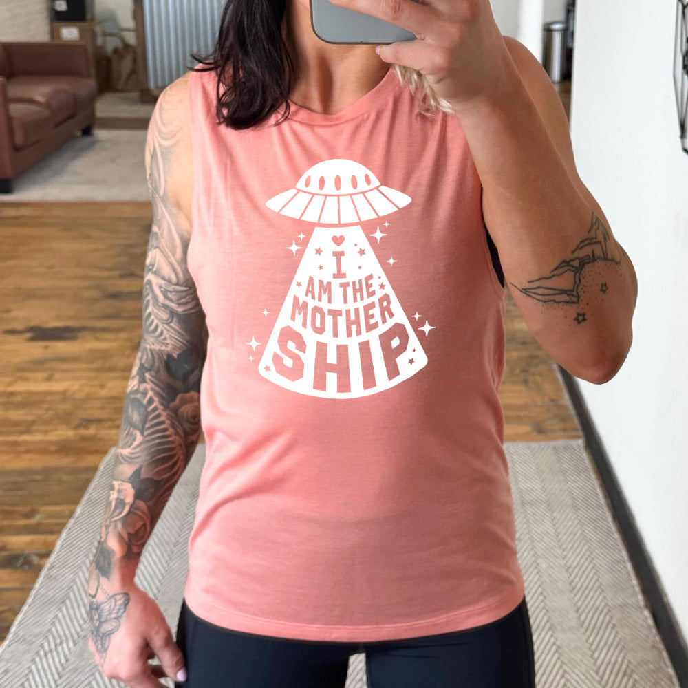 peach muscle tank with the words "I am the mothership" on it within the beam of a UFO, with a heart above the words, and a number of stars scattered around