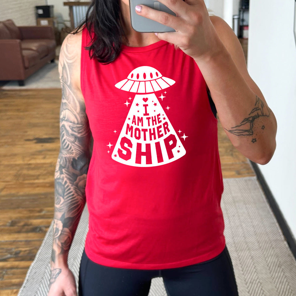 red muscle tank with the words "I am the mothership" on it within the beam of a UFO, with a heart above the words, and a number of stars scattered around