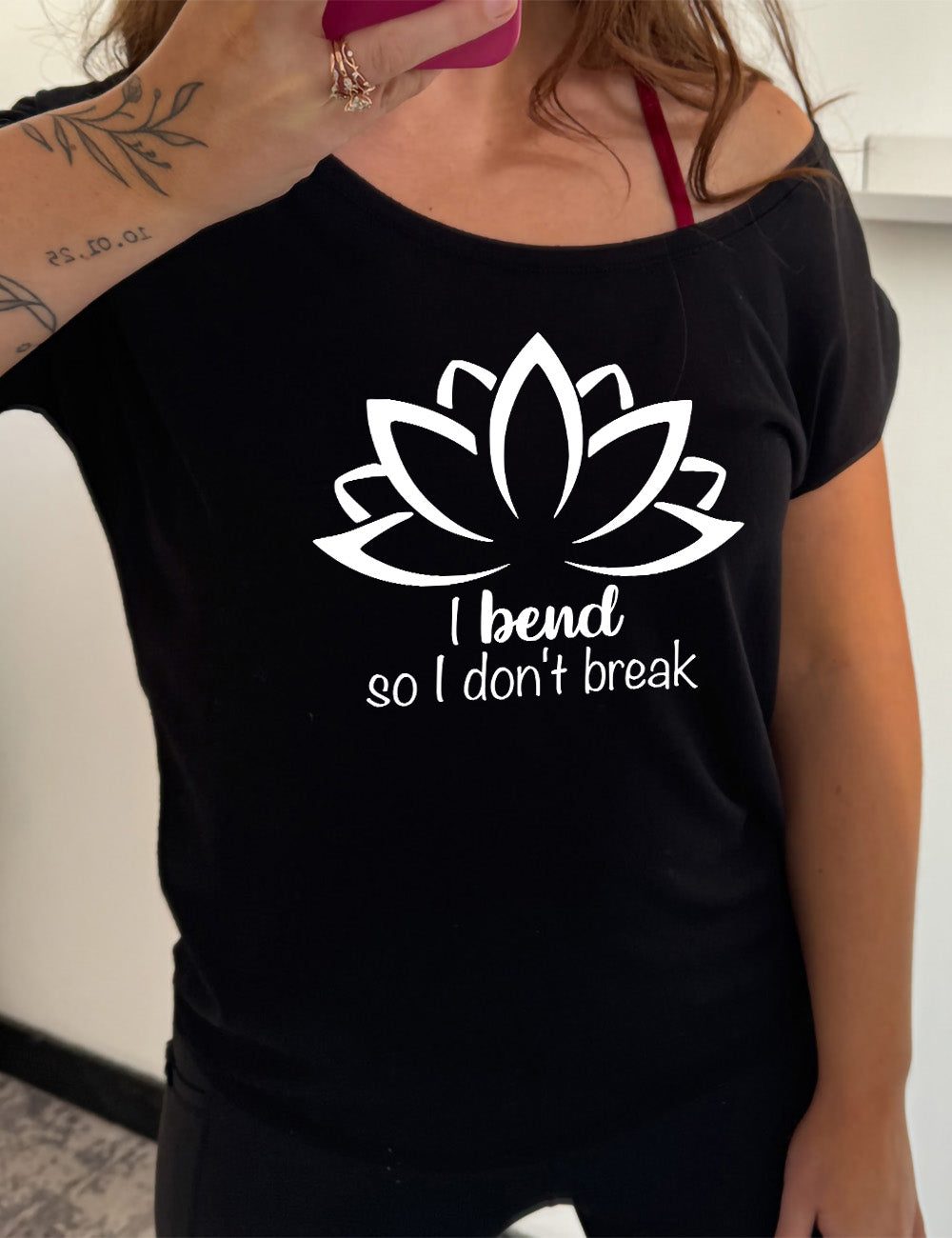 black slouchy tee with the graphic silhouette of a lotus and the words underneath saying "I bend so I don't break"