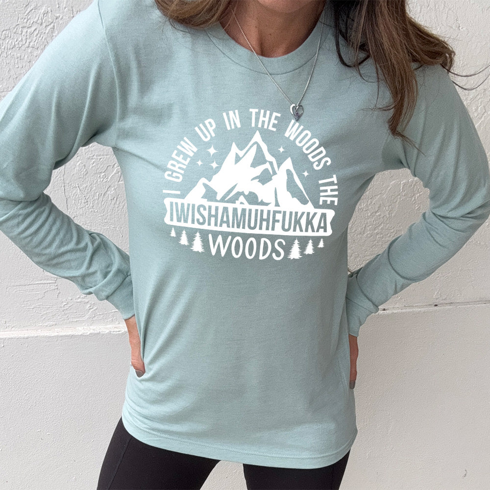 heather dusty blue long sleeve with the words "I grew up in the woods the Iwishamuhfukka woods" on it, with the graphic of mountains and trees and stars