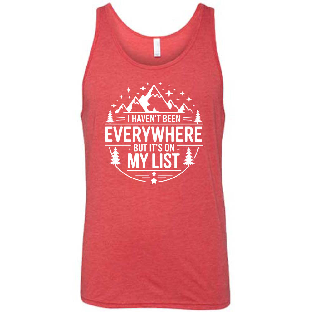 red unisex tank with the words "I haven't been everywhere but it's on my list" as part of a circular design involving the graphic of small mountains on top and a few trees on the sides and stars scattered around