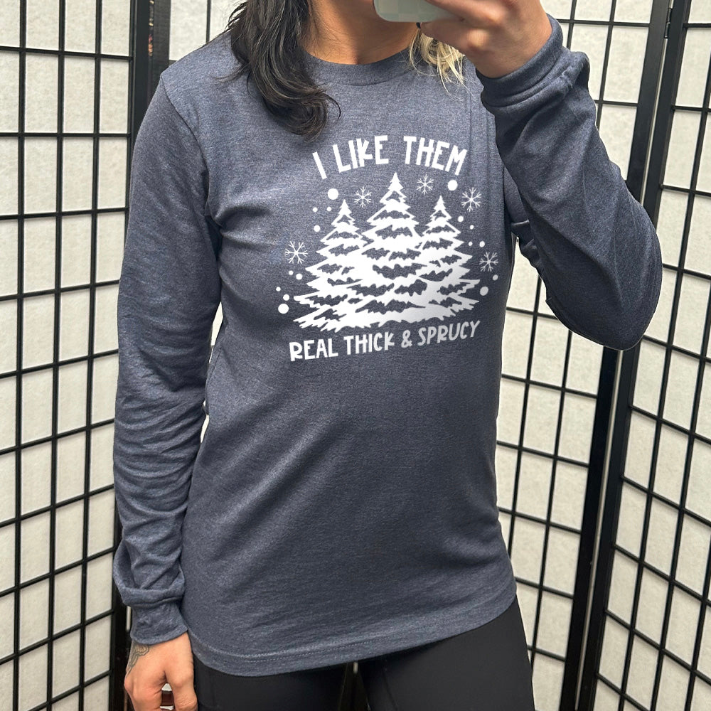 heather navy long sleeve with the words "I like them real thick & sprucy" and the graphics of big christmas trees and smaller snowflakes