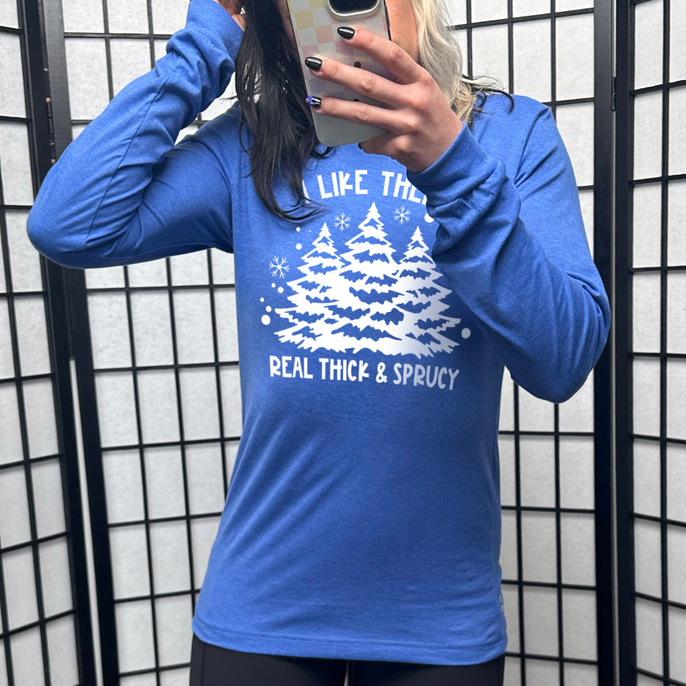 heather true royal long sleeve with the words "I like them real thick & sprucy" and the graphics of big christmas trees and smaller snowflakes