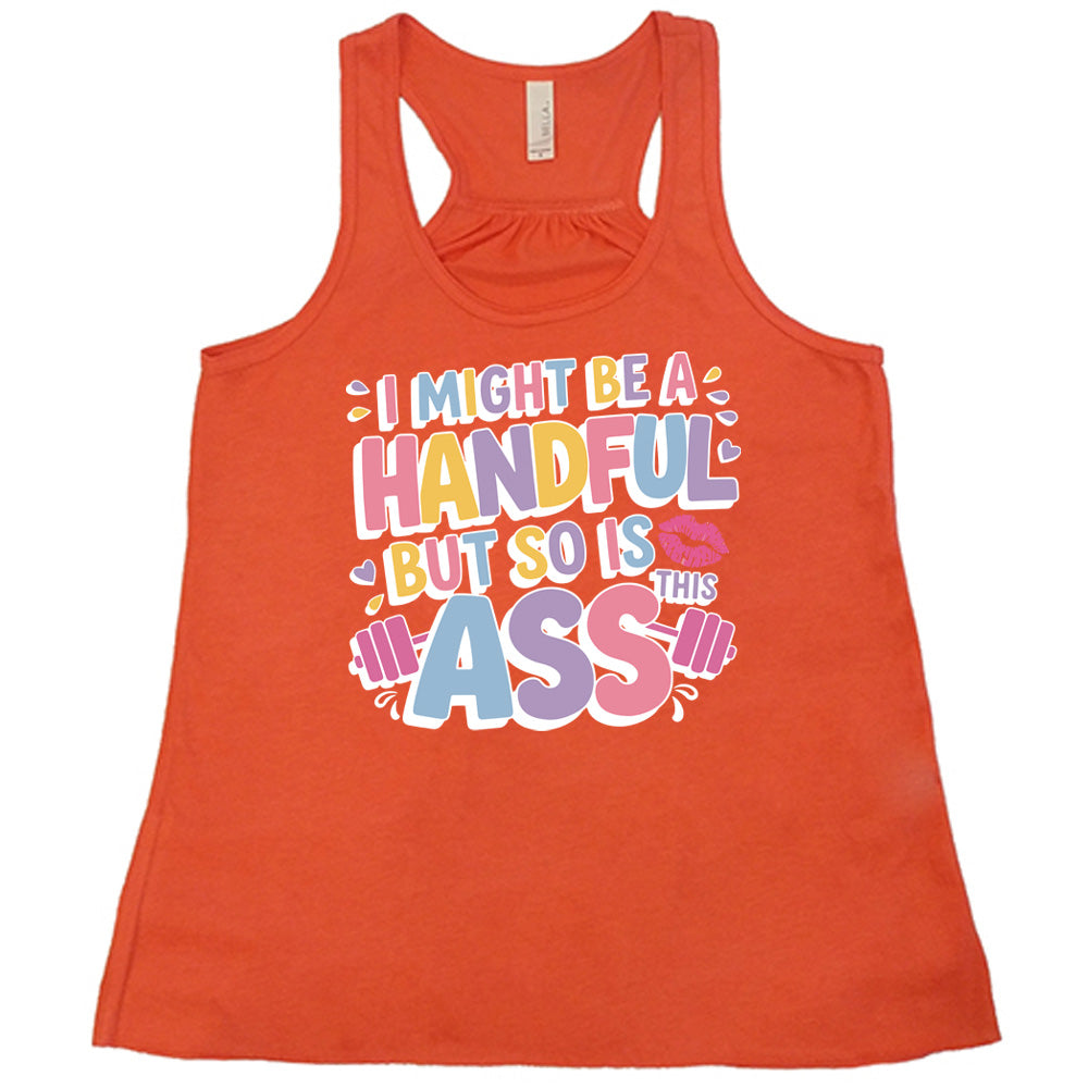 coral flowy tank with the words "I might be a handful but so is this ass" in a colorful font, with a barbell as part of the word "ass", and a few little hearts and a kissing lips graphic