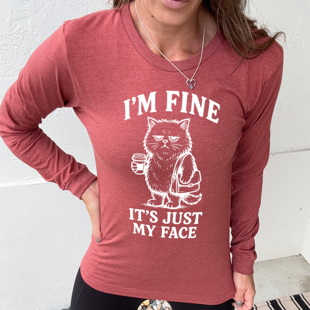 heather clay long sleeve shirt with the words "I'm fine it's just my face" on it, around the graphic of a cat with a resting-grumpy face, holding a coffee and wearing a purse