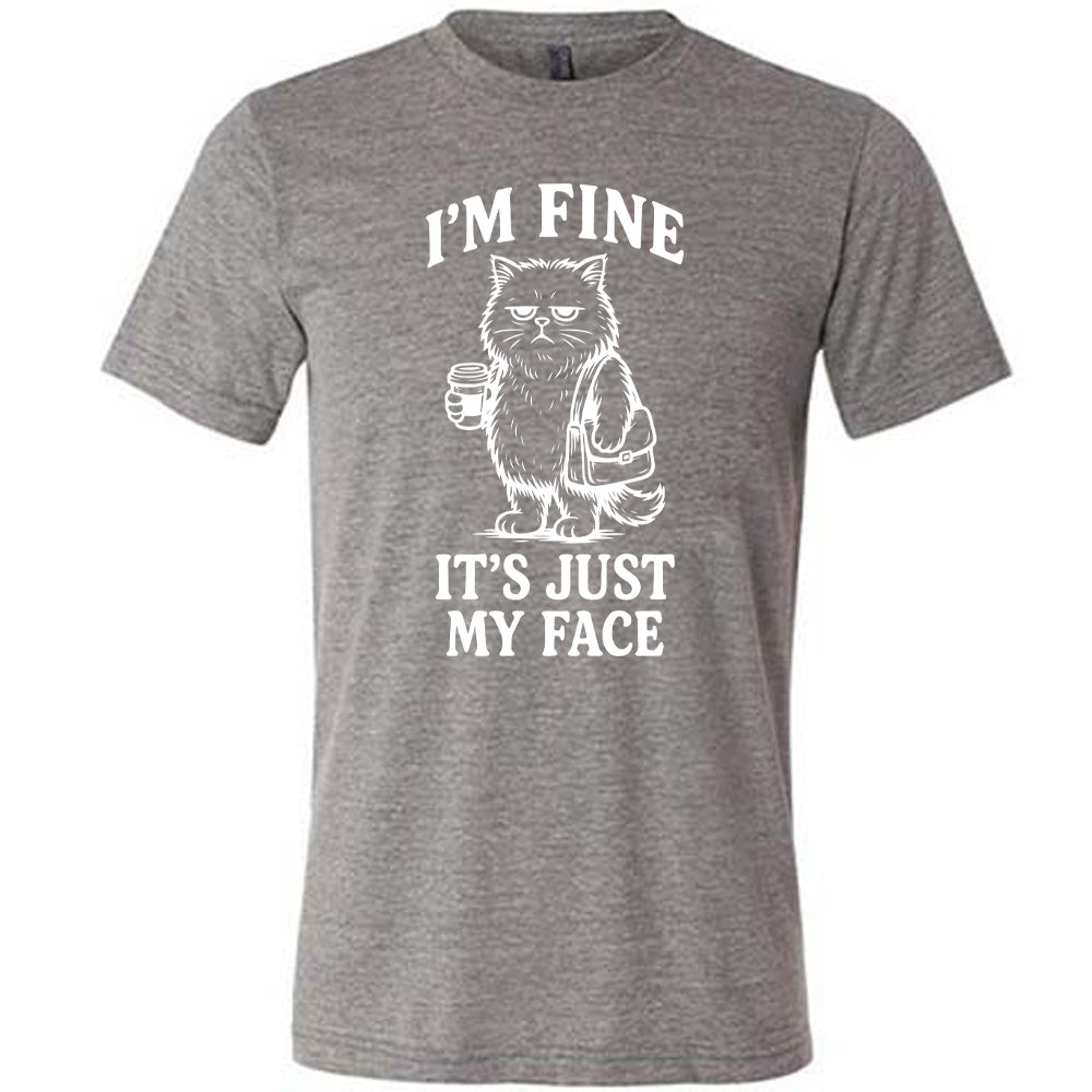 grey unisex tee with the words "I'm fine it's just my face" on it, around the graphic of a cat with a resting-grumpy face, holding a coffee and wearing a purse