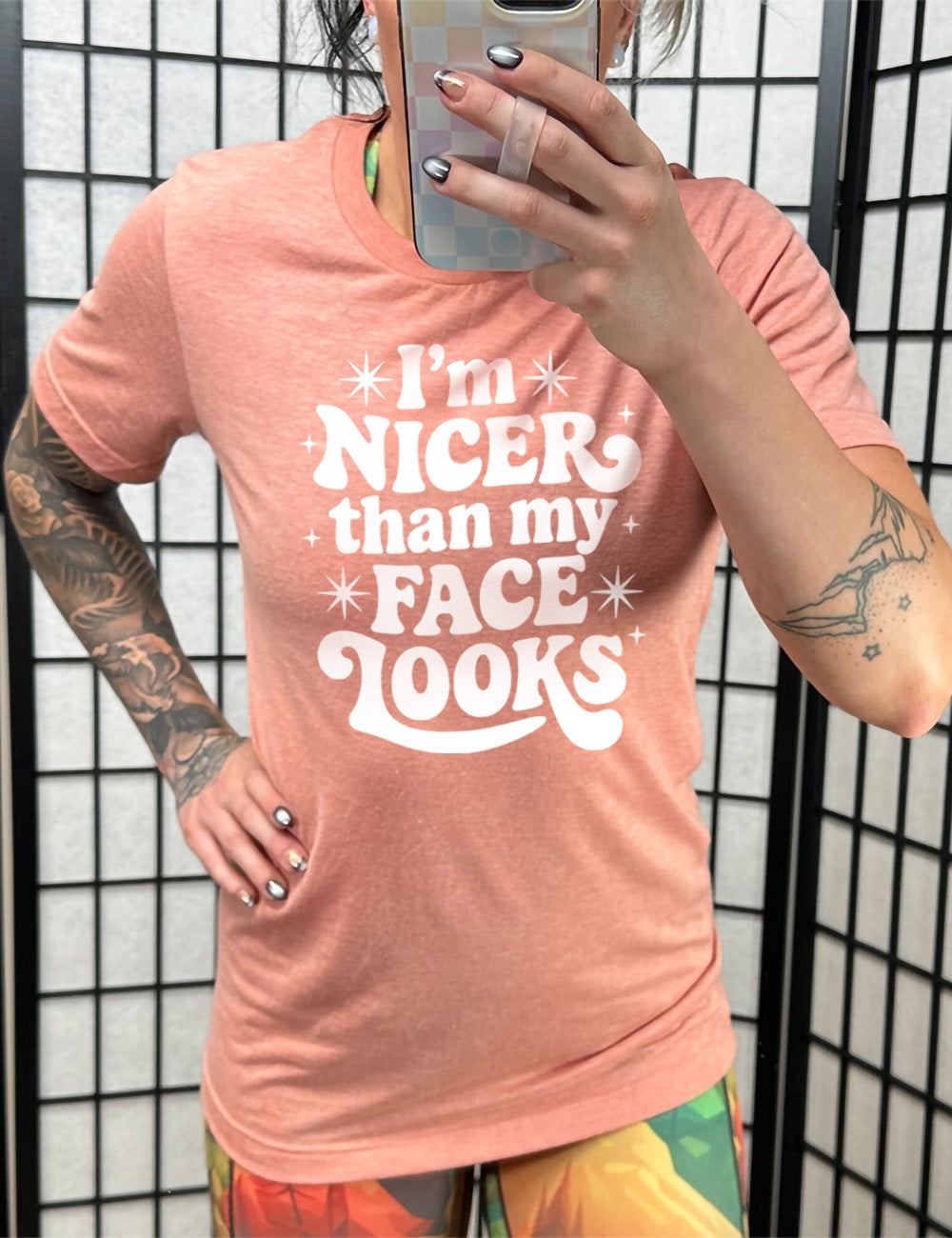 sunset unisex tee with the words "I'm nicer than my face looks" surrounded by stars