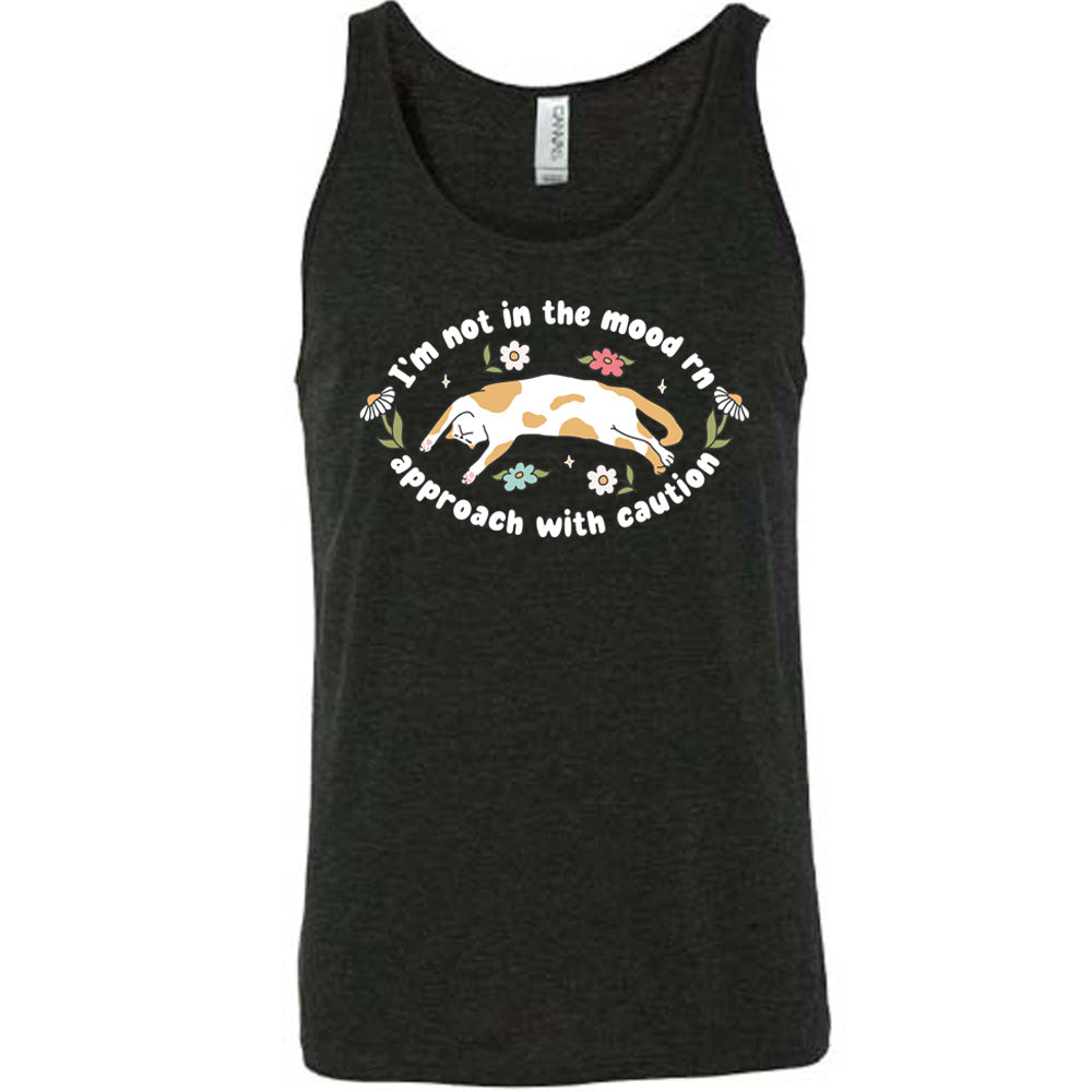 black unisex tank with the words "I'm not in the mood rn approach with caution" on it in an oval, with the graphic of a cat splayed on its back within the words, and a few flowers around