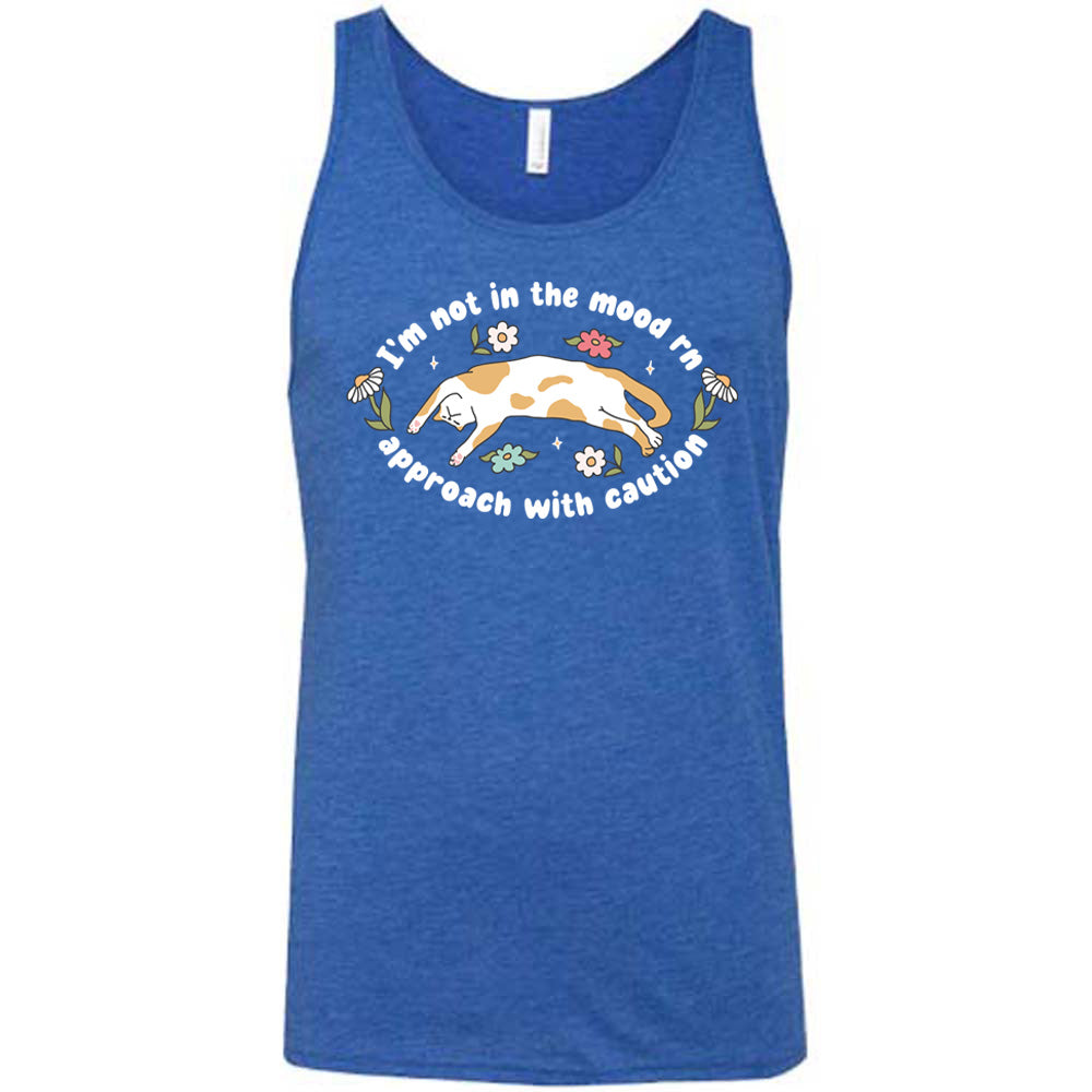 blue unisex tank with the words "I'm not in the mood rn approach with caution" on it in an oval, with the graphic of a cat splayed on its back within the words, and a few flowers around