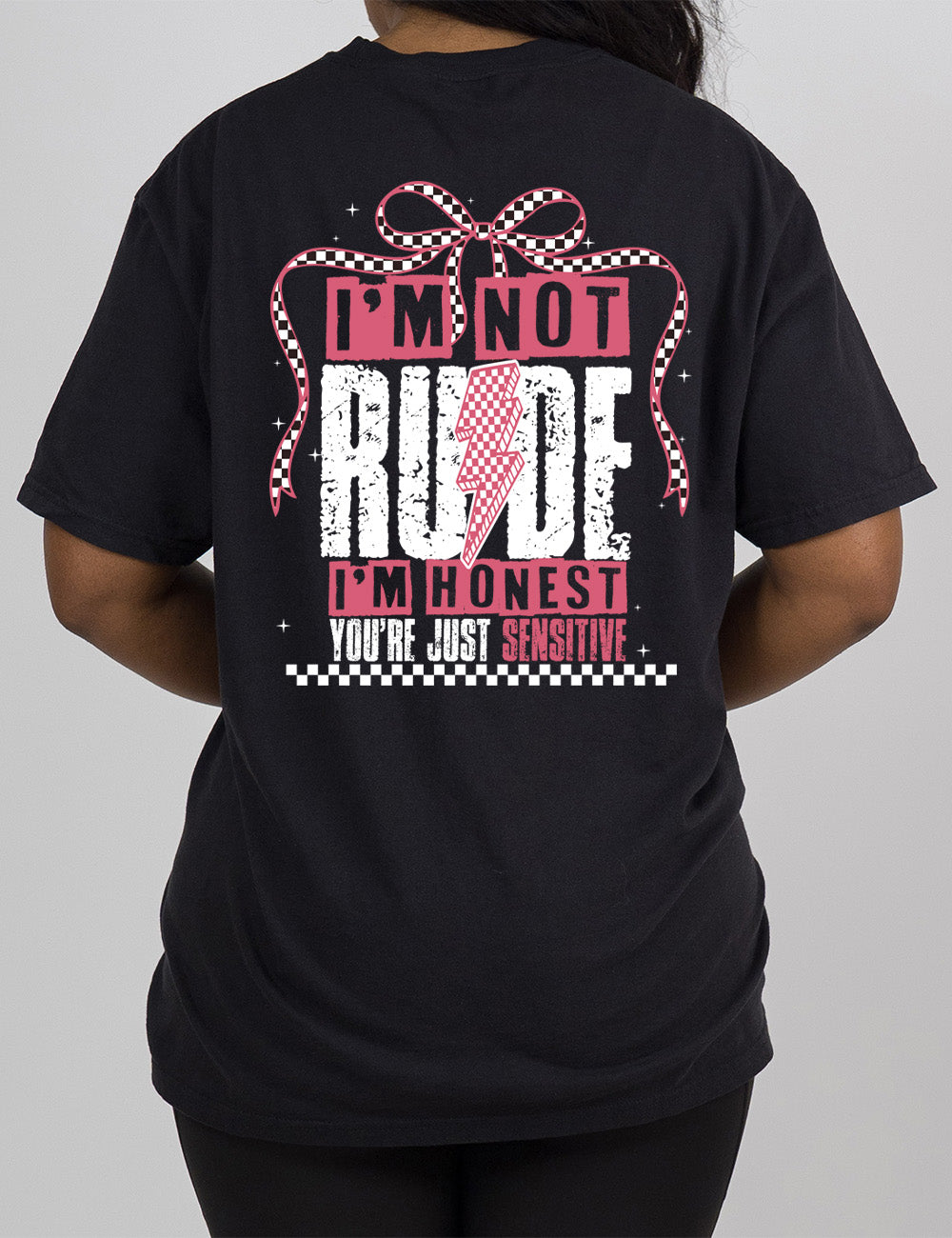 black modern tee with print placement on the back, in punk style, with the words "I'm not rude I'm honest you're just sensitive" on it, with a checkered lightning bolt in the middle of the word "rude" and a checkered bow arching over the words, and a checkered band below them, and a few small stars scattered around