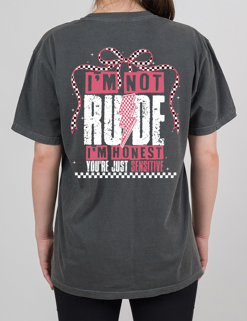 pepper modern tee with print placement on the back, in punk style, with the words "I'm not rude I'm honest you're just sensitive" on it, with a checkered lightning bolt in the middle of the word "rude" and a checkered bow arching over the words, and a checkered band below them, and a few small stars scattered around
