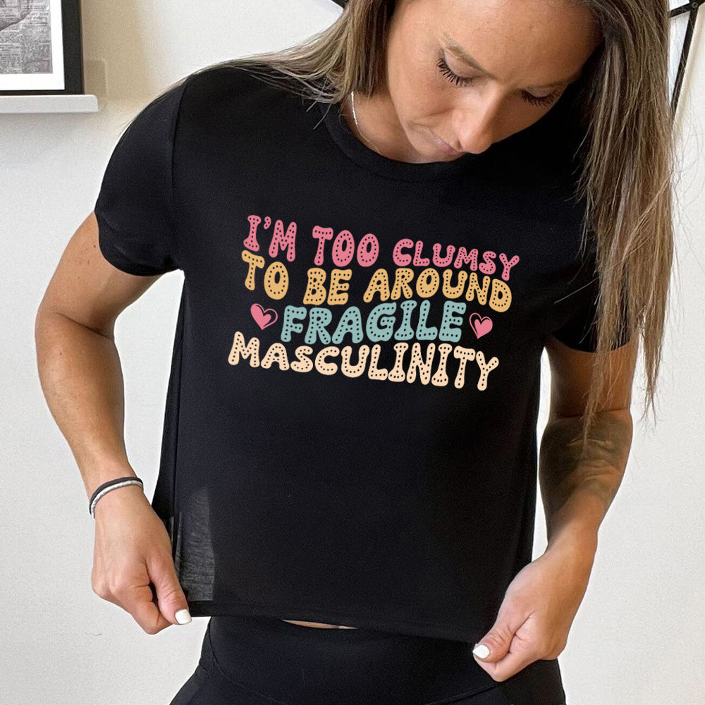 Model wearing black cropped tee with a graphic on it that says "I'm Too Clumsy To Be Around Fragile Masculinity"