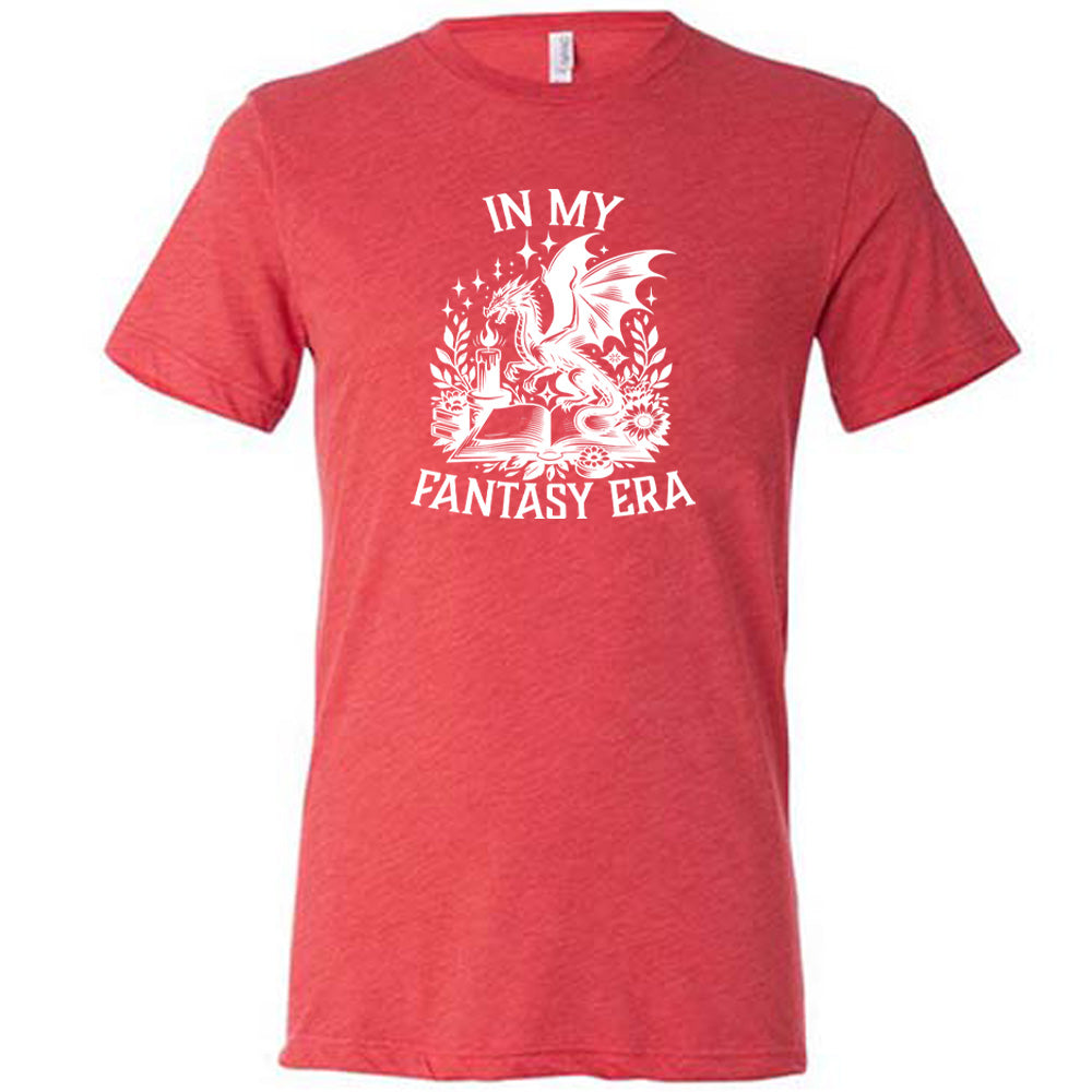 Red colored shirt with a dragon lighting a candle over a book graphic on it that says "In My Fantasy Era"
