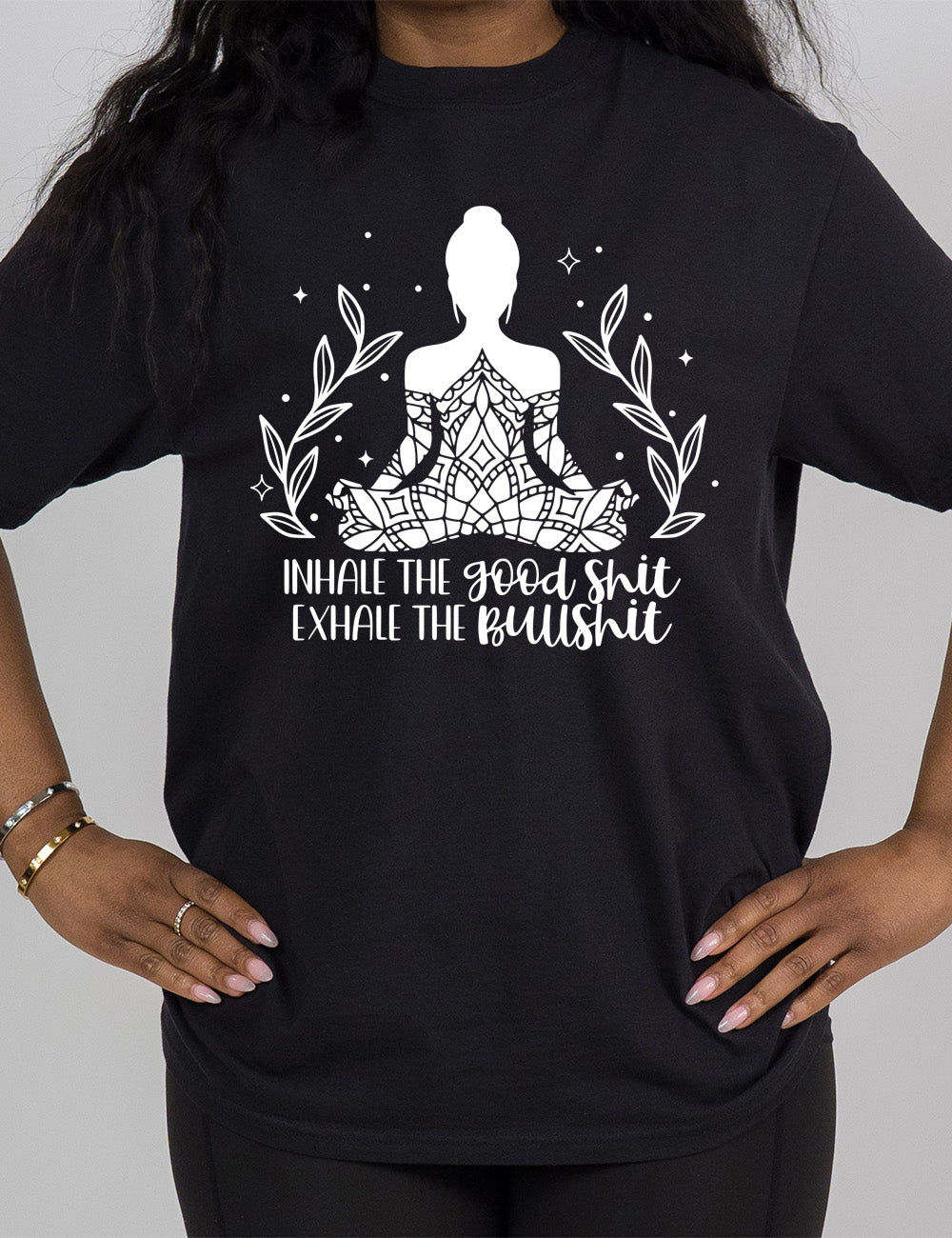 black modern tee with the graphic of a woman's silhouette (partially covered in elaborate shapes) with a plant on either side, surrounded by little stars, and the words underneath saying "Inhale the good shit exhale the bullshit"