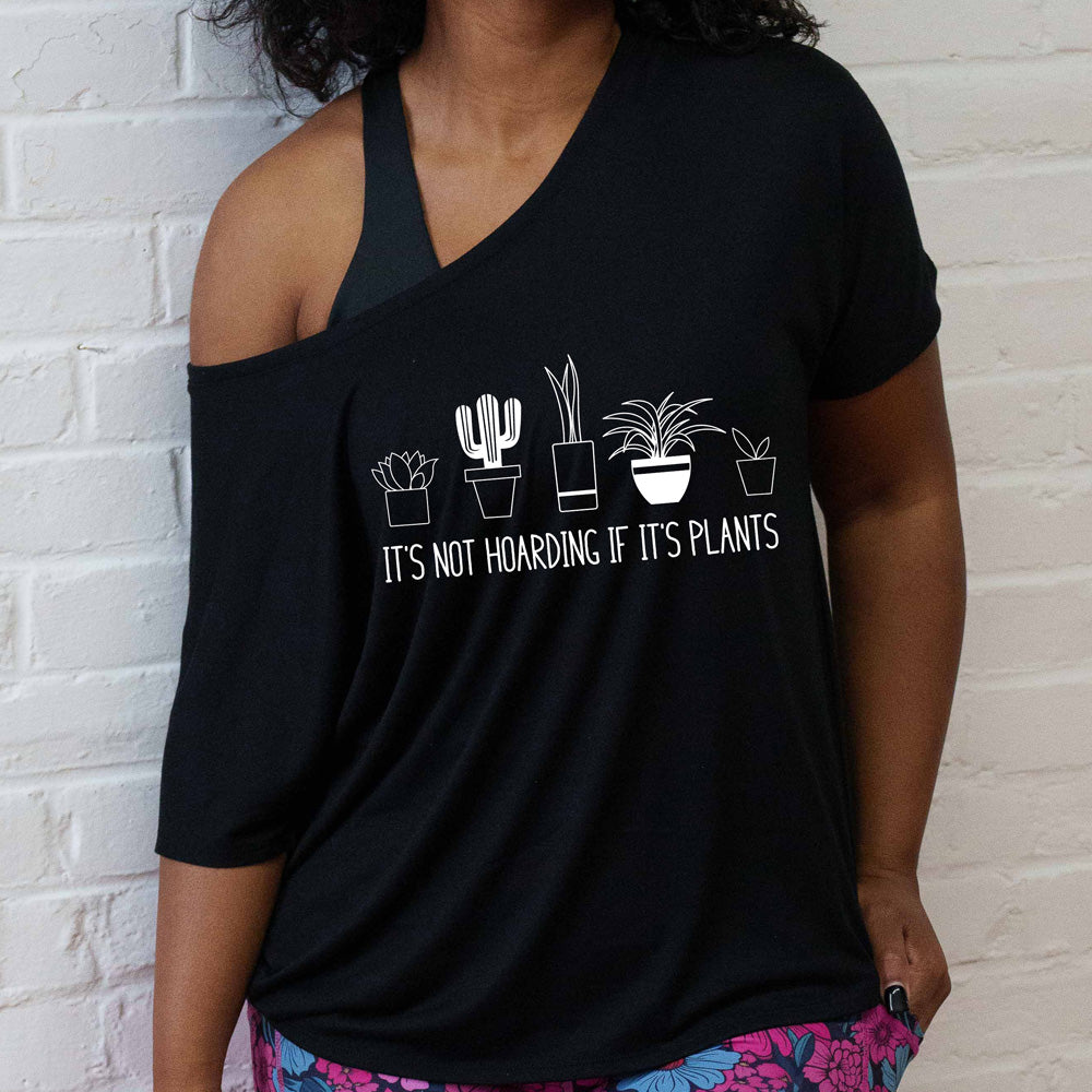 Person wearing a black t-shirt with a plant-themed design against a white brick wall.