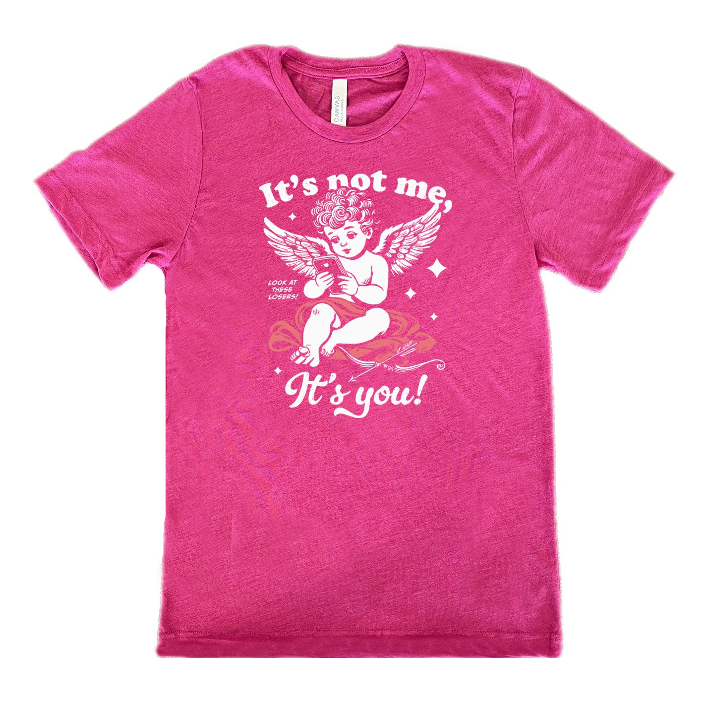 berry unisex tee with the words "it's not me, it's you!" on it, with graphics of Cupid looking at a cell phone (presumably looking at dating apps), with small words saying "look at these losers!" and Cupid's bow and arrow at his side